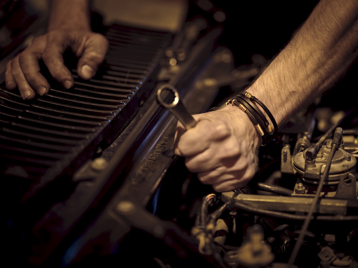 Mechanic working on an engine bay with a wrench